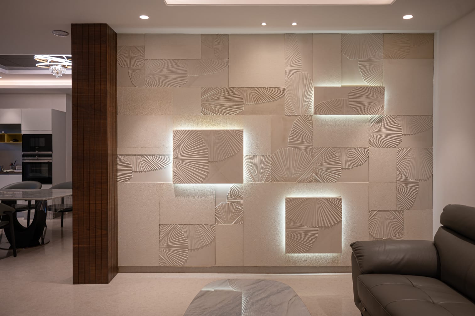 Modern luxury dining room with dining table, upholstered chairs, chandelier, and carved stone accent wall