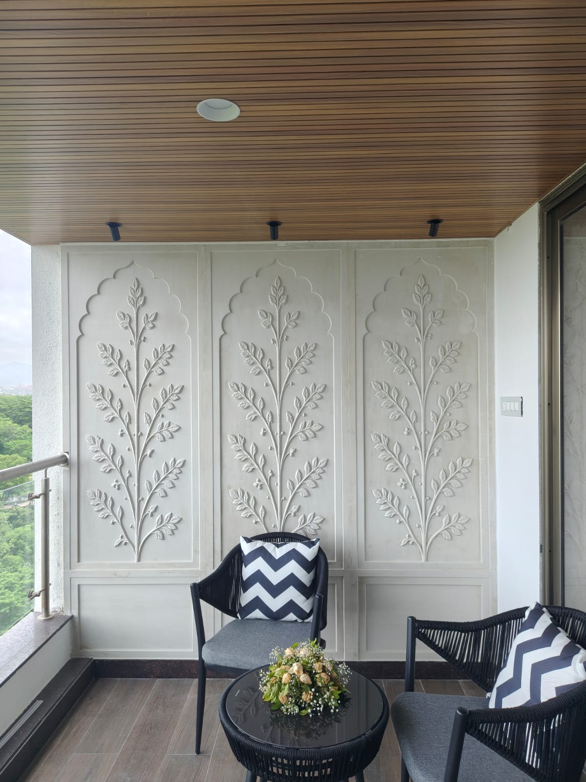 Intimate dining setting with round dining table and bistro chairs set against an ornate carved sandstone jharokha wall