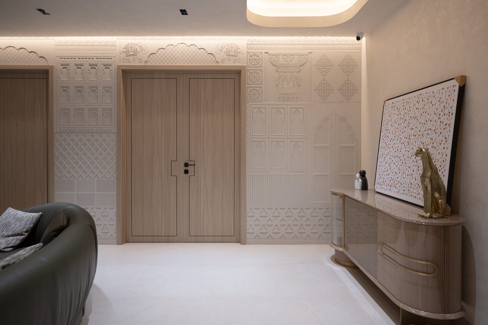 Grand residential entrance foyer featuring double doors framed by hand-carved sandstone Rajasthani arch with royal elephant motifs