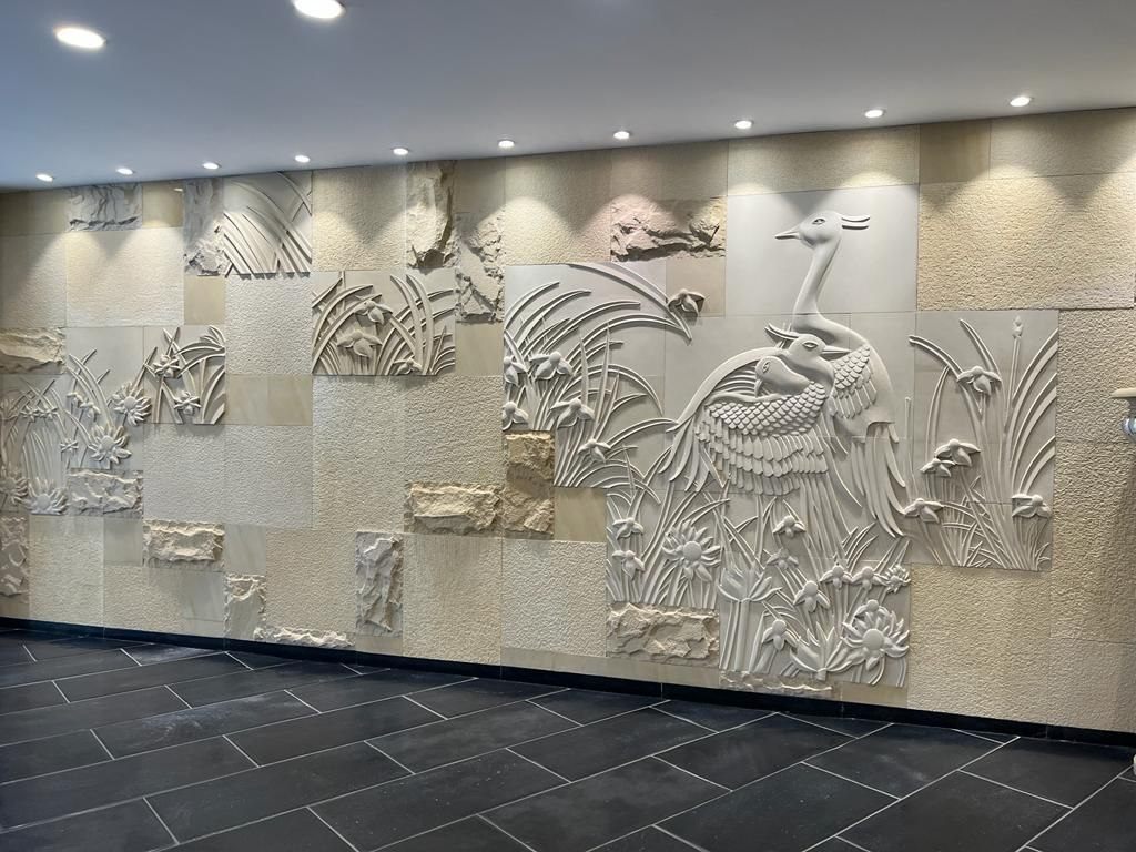 Entrance hallway corridor wall mural featuring sculpted crane birds and blooming lotus pond in natural sandstone