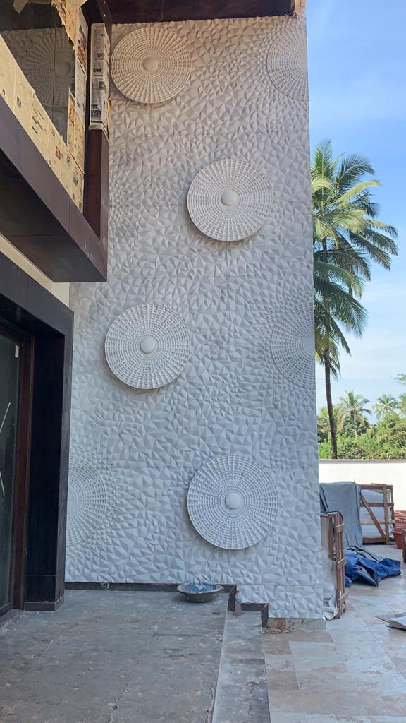 Exterior open-air veranda courtyard with geometric sandstone relief wall under open sky