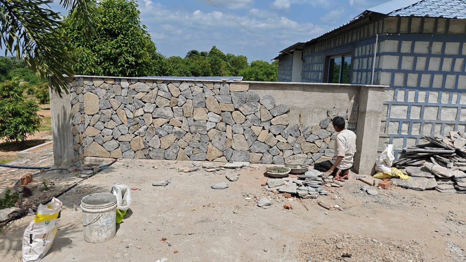 Artisan stonemason hand-fitting exterior dry-stone boundary wall in natural sunlight