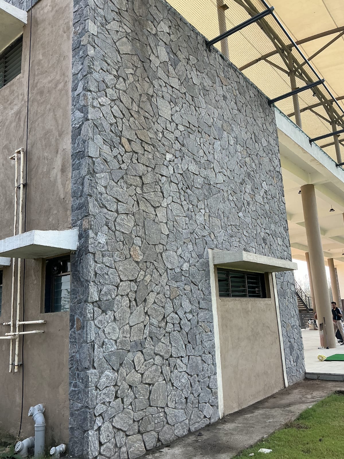 Multi-level building exterior facade clad in grey rustic natural stone masonry