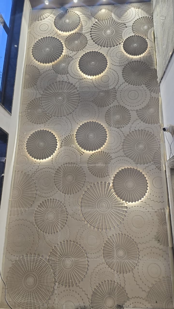 Interior double-height architectural stone wall with circular carved geometric relief and warm ambient backlight