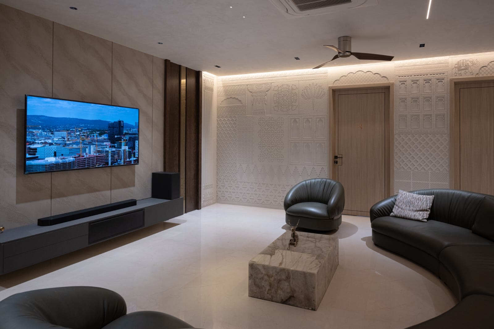 Large television mounted on seamless monolithic natural stone backdrop with long floating media console